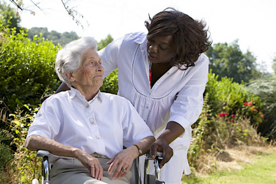 afro-american caregiver talking to disabled senior woman